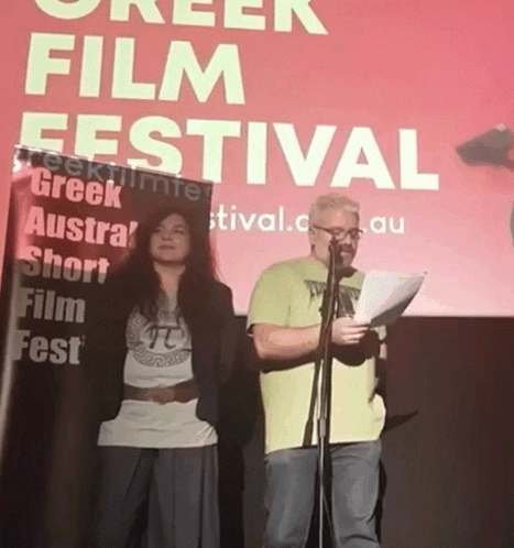 Man and Woman Standing at Greek Film Festival Sign