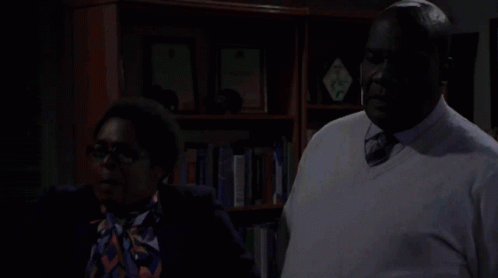 Man and Woman Standing in Front of Bookshelf