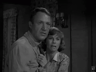 Man and Woman Standing in Room Looking at Something
