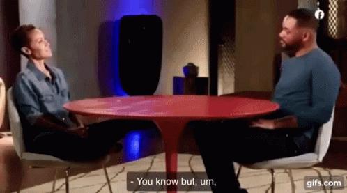Man and Woman Talking at Red Table