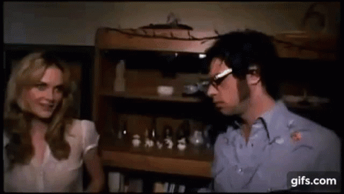 Man And Woman Talking By Bookshelf GIF