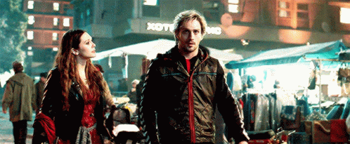 Man and Woman Walking Down Street in Front of Store