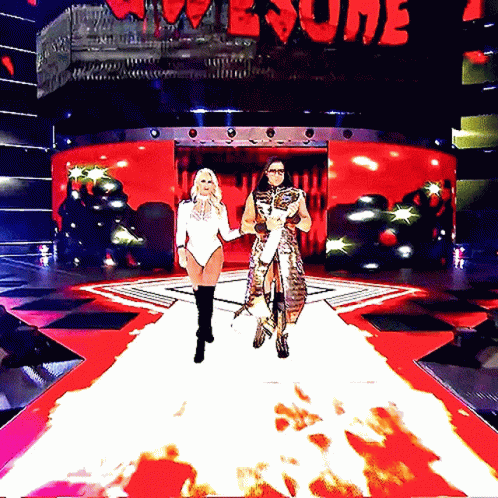 Man and Woman Walking on Stage in Front of Home Sign
