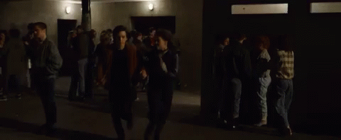 Man and Woman Walking Through Crowd in Dark Room