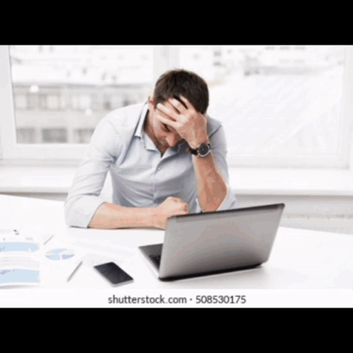 Man at Desk with Hands on Head in Front of Laptop
