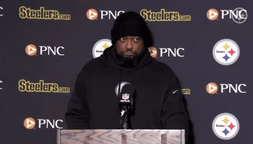 Man at Podium in Front of Wall Saying Steelers.com