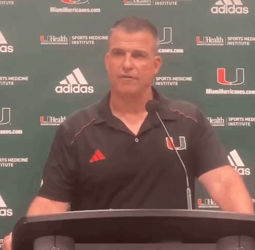 Man at Podium with Miami Hurricanes Banner