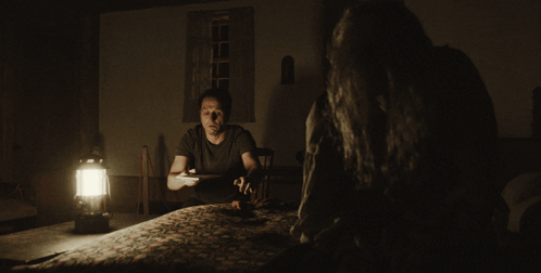 Man at Table in Dark Room with Lantern