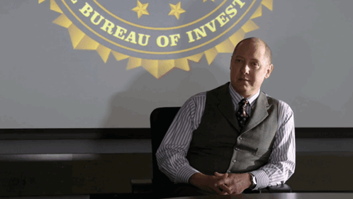 Man At Table In Front Of Bureau Of Invest Screen GIF