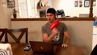 Man at Table with Laptop and Red Gun Supreme
