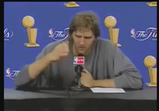Man At Table With Microphone In Front Of NBA Trophies GIF