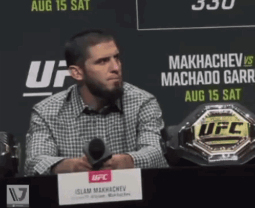 Man At Table With Microphone In Front Of UFC Sign GIF