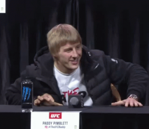 Man at Table With Paddy Pimblett Sign