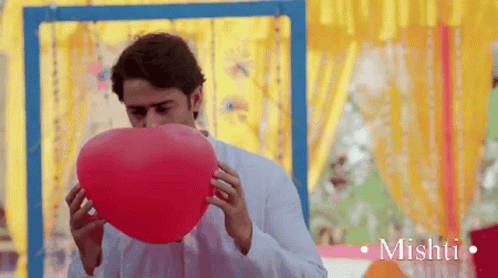 Man Blowing Up Red Balloon With Mishti