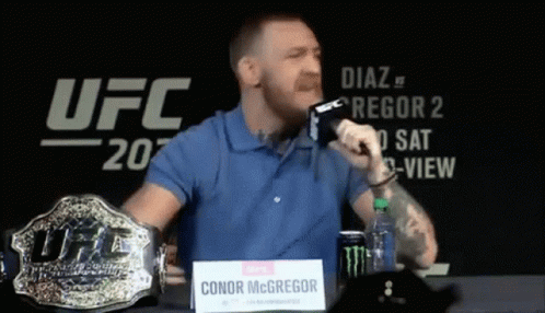 Man Blue Shirt Holding Microphone and UFC Belt