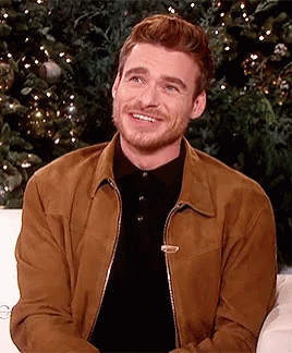Man Brown Jacket Black Shirt Smiling On Couch GIF