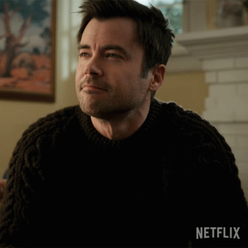Man by Fireplace in Black Sweater Netflix Logo
