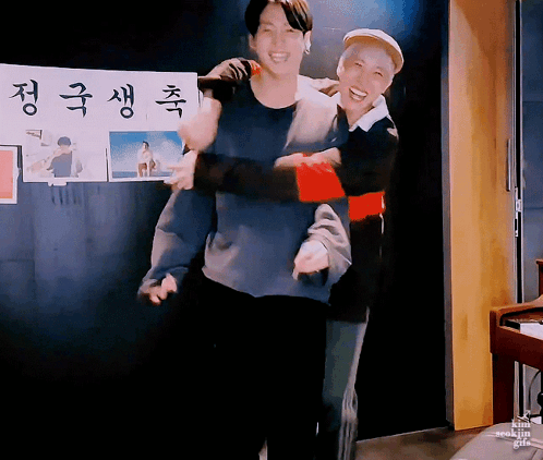 Man Carrying Another Man in Front of Korean Sign