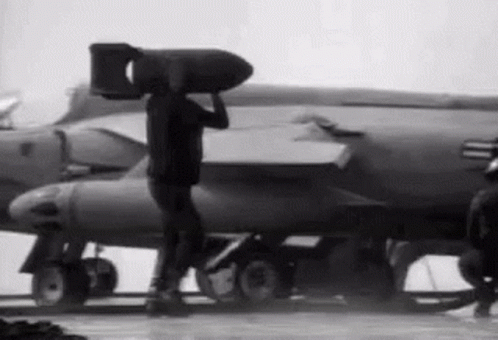 Man Carrying Large Bomb in Front of Jet