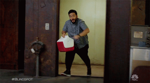 Man Carrying Red and White Cooler With NBC Logo