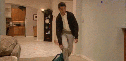 Man Carrying Suitcase Through Living Room