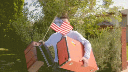 Man Carrying Suitcases With American Flag Over Face