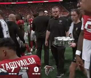 Man Carrying Tray Of Cans On Field GIF