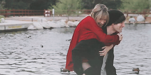 Man Carrying Woman on Back at Lake