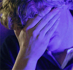 Man Covering Face With Hand in Front of Blue Light