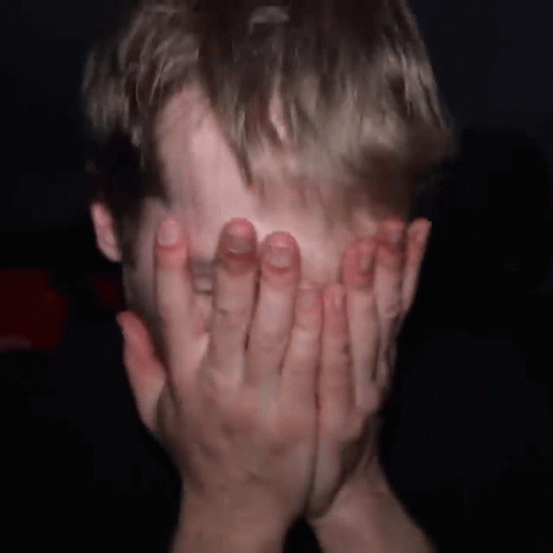 Man Covering Face With Hands in Dark Room