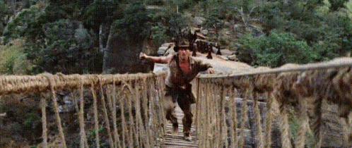 Man Crossing Rope Bridge in Woods