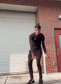Man Dancing in Front of Brick Building With White Garage Door