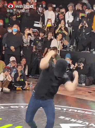 Man Dancing In Front Of Crowd With Weibo Logo GIF