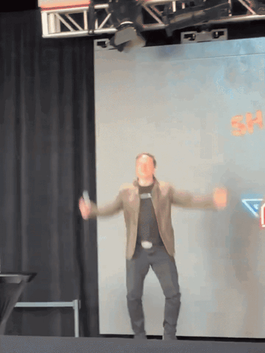 Man Dancing on Stage With Sign Saying sh