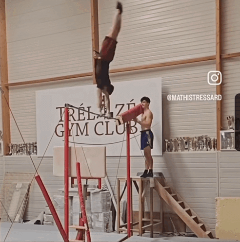 Man Doing Handstand in Front of Gym Banner