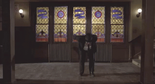 Man Doing Trick In Front Of Stained Glass Window With Letter G GIF