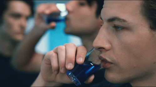 Man Drinking From Shot Glass With Blue Liquid