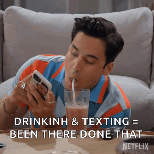 Man Drinking Through Straw Looking at Phone