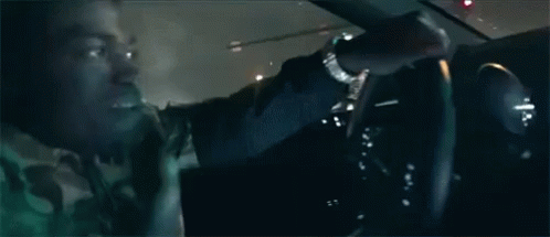 Man Driving Car at Night With Another Looking On