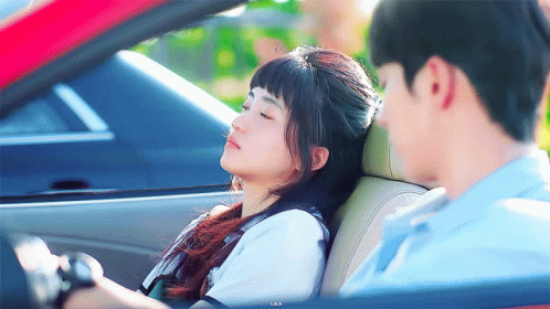 Man Driving Red Car With Woman Sleeping in Back Seat