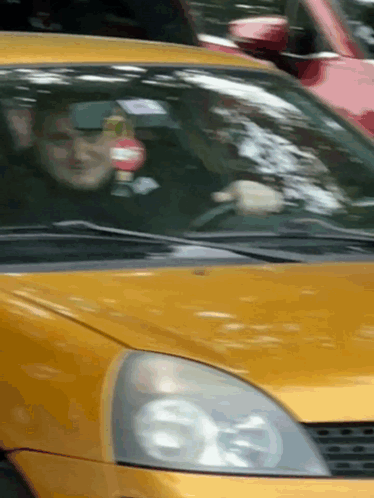 Man Driving Yellow Car With Red And White Sign GIF