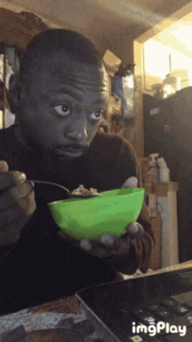 Man Eating from Green Bowl with Spoon