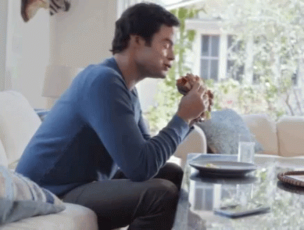Man Eating Hamburger On Couch GIF