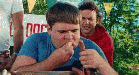 Man Eating Hot Dog Beside Sign Saying Dog