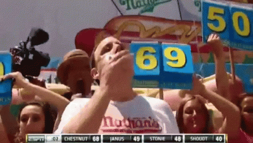 Man Eating Hot Dog Holding 69 Sign