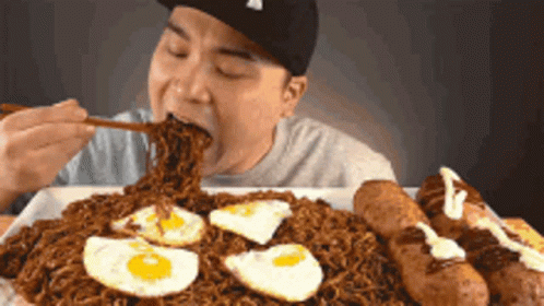 Man Eating Noodles with Eggs and Sausages