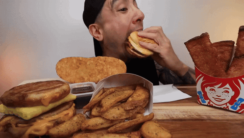 Man Eating Wendy's Sandwich Next to French Fries