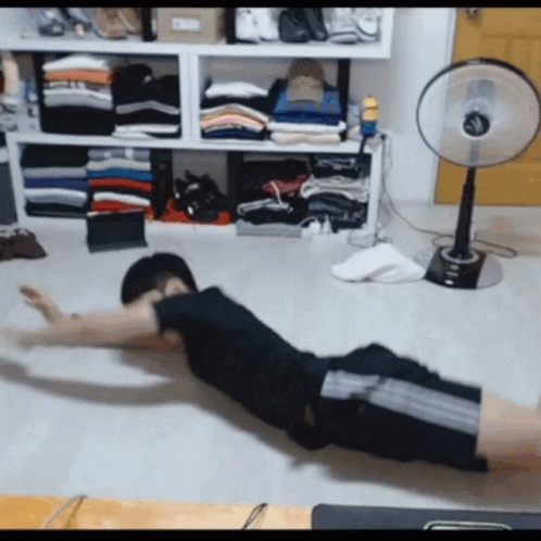 Man Exercising on Floor in Front of Fan and Clothes