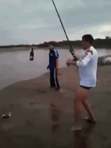 Man Fishing on Beach With Bottle
