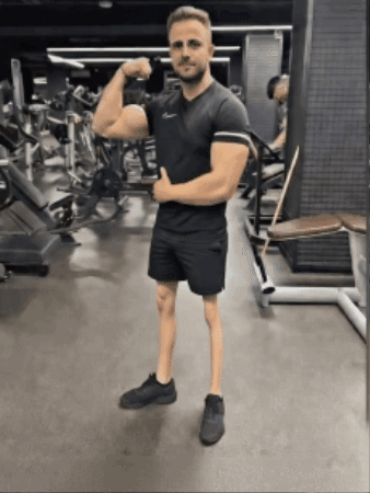 Man Flexing Muscles in Gym While Wearing Shorts